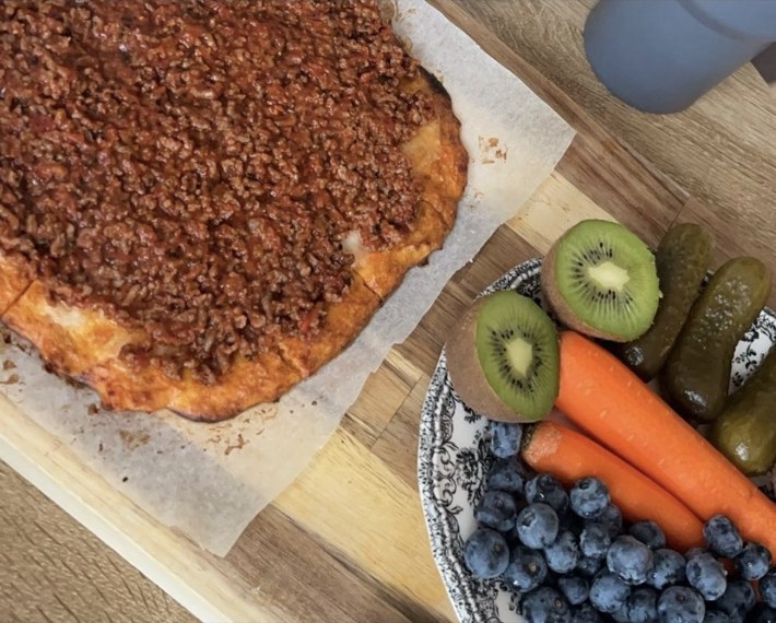 Hjemmelaget pizza med frukt og grønt ved siden av